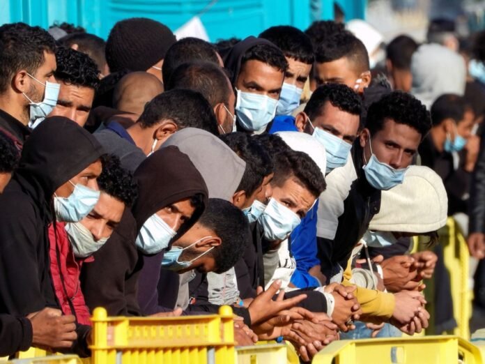 Grupo de inmigrantes con mascarillas esperando en la frontera española durante este invierno.