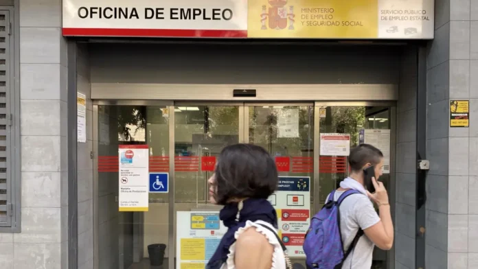 Entrada de una oficina de empleo española con personas accediendo al servicio público de empleo estatal,