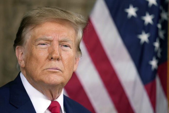 Donald Trump, expresidente de Estados Unidos, con expresión seria frente a la bandera americana