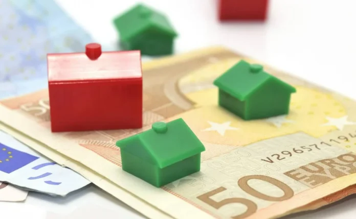 Casas de Monopoly rojas y verdes sobre billetes de euro, representando inversiones inmobiliarias y mercado de la vivienda en Europa